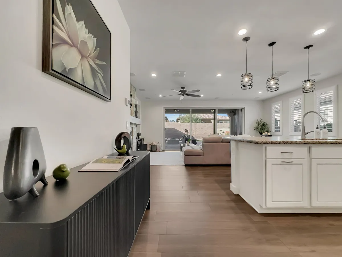 A modern kitchen featuring sleek cabinetry, a spacious kitchen island perfect for meal prep or casual breakfasts, decorative artwork, and an open window offering a view outside. The layout feels airy and inviting, designed to accommodate both cooking and entertaining.