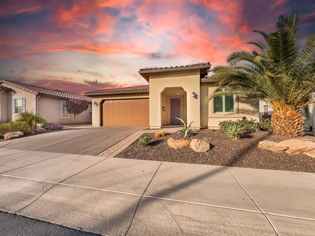 A beautifully landscaped home entrance featuring a palm tree, inviting porch, and a tidy garage door. The scene is set for welcoming guests, enjoying relaxed evenings outdoors, or sipping morning coffee amidst greenery, conveying a strong sense of community and home base.