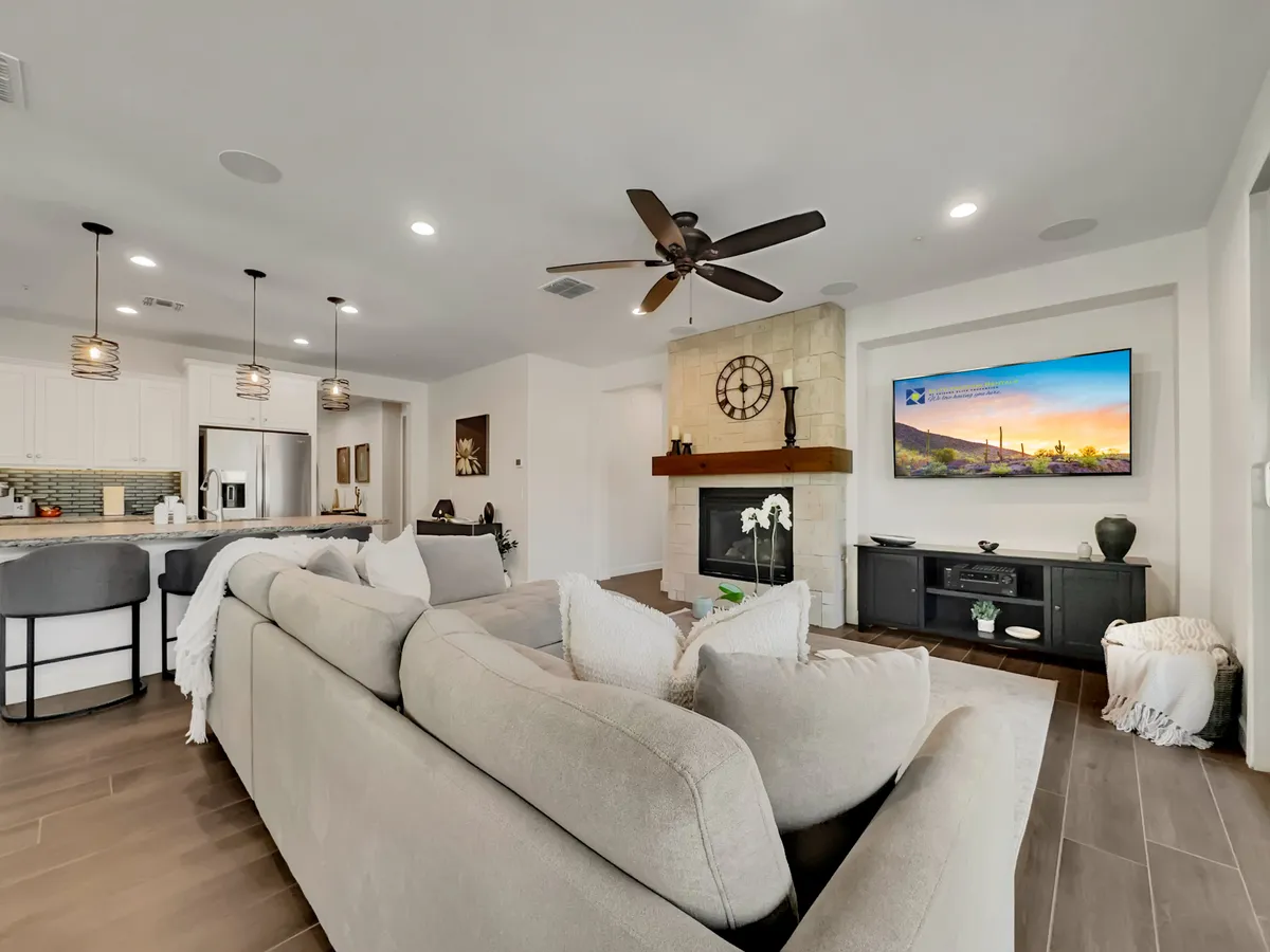 This image features a comfortable sectional sofa arranged around a modern fireplace with a television mounted above. Pendant lights offer a warm glow, and the space feels cozy yet open, ideal for both relaxation and entertaining guests.