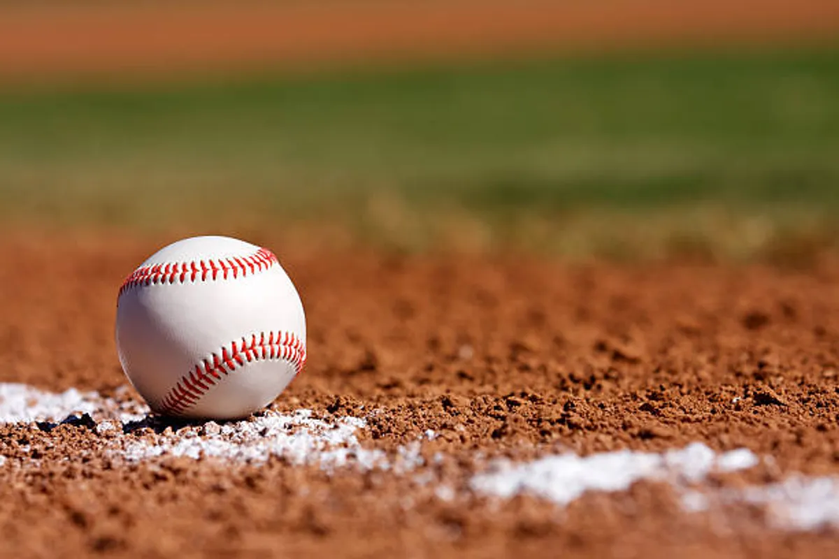 An exterior view capturing a dirt baseball field with a baseball and white chalk line, evoking a sense of outdoor recreation and community activities. The field is open, with a warm, nostalgic atmosphere that invites thoughts of family outings and local sports.